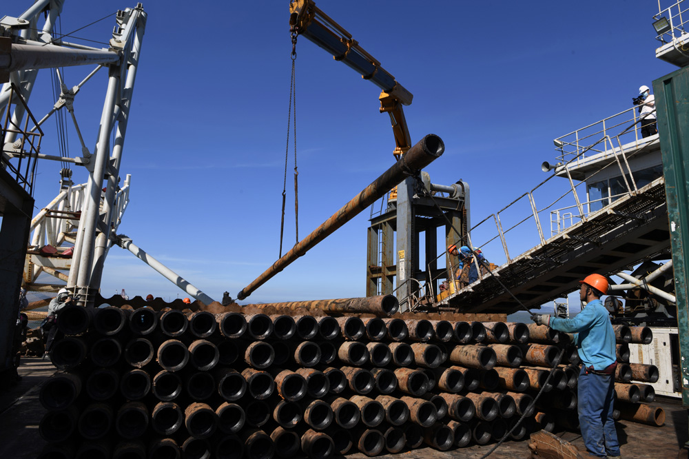 建設者在原油管道穿越時進行吊裝鉆桿。朱將云攝