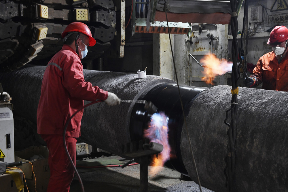 建設者對原油管道進行熱縮帶防腐作業。朱將云攝