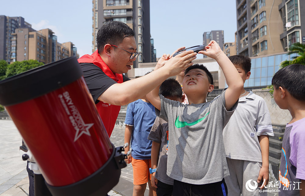 來自寧波天文愛好者協會的“甬愛幫幫團”志愿者郭皓帶領“小候鳥”們觀察太陽黑子。人民網 章勇濤攝
