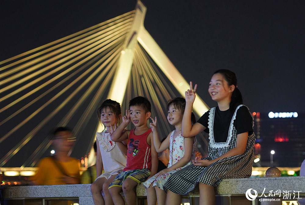 幾位青少年在寧波老外灘江畔乘涼，并拍照留念。人民網 章勇濤攝