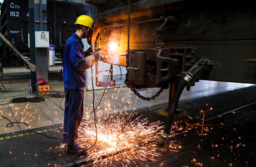 倪高明為貨車端部破損處焊接上新鐵板。汪晟攝