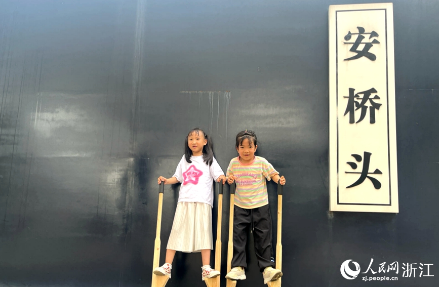 小朋友踩著高蹺，在夢回平橋公園門口玩耍。人民網記者 張麗瑋攝