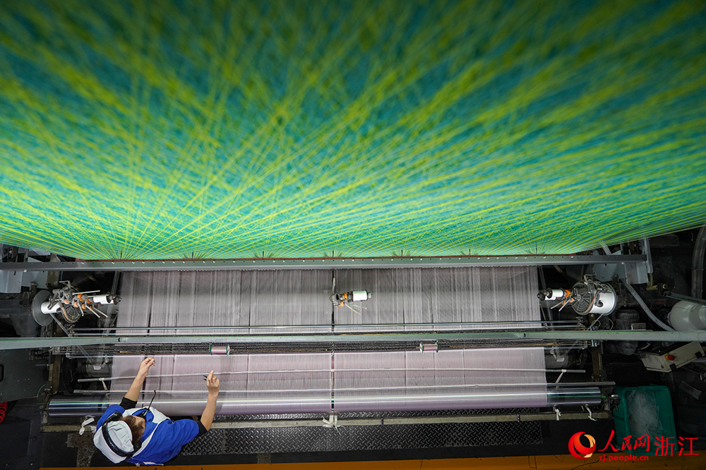 浙江省紹興市新昌縣達利絲綢智能工廠內一派繁忙，工人在生產線上趕制訂單。人民網 章勇濤攝