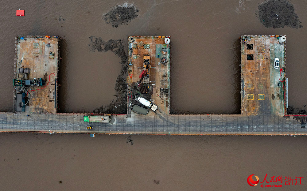 3月12日，在寧波市鎮海區灰鱉洋南岸灘涂之上，工人在棧橋搭建起的海上施工通道上有序施工。人民網 章勇濤攝