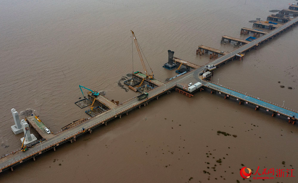 3月12日，在寧波市鎮海區灰鱉洋南岸灘涂之上，工人在棧橋搭建起的海上施工通道上有序施工。人民網 章勇濤攝