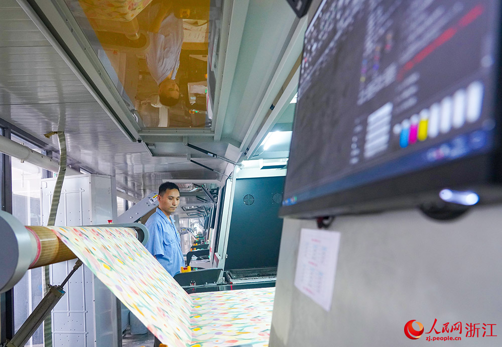 在浙江省紹興市柯橋區的印染企業，工人在數碼印花產線上趕制訂單。人民網 章勇濤攝