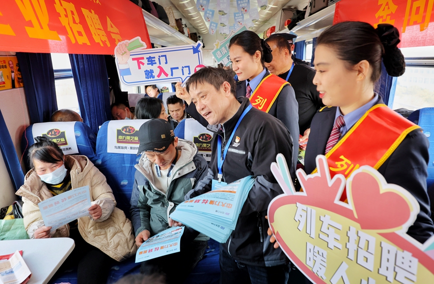 企業工作人員正在車廂里向旅客發放招聘公告。周圍攝