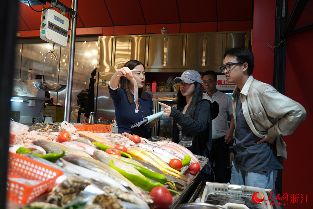 在舟山沈家門夜排檔，一位老板娘正在向顧客介紹食材。人民網 陳陸洵攝