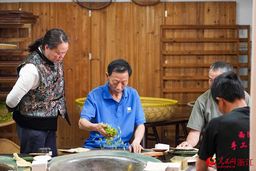 在杭州市西湖區轉塘街道桐塢村，國家級非物質文化遺產代表性項目“西湖龍井采摘和制作技藝”傳承人樊生華（中）在傳授學徒胡芳（左）炒制茶葉技藝。人民網 章勇濤攝