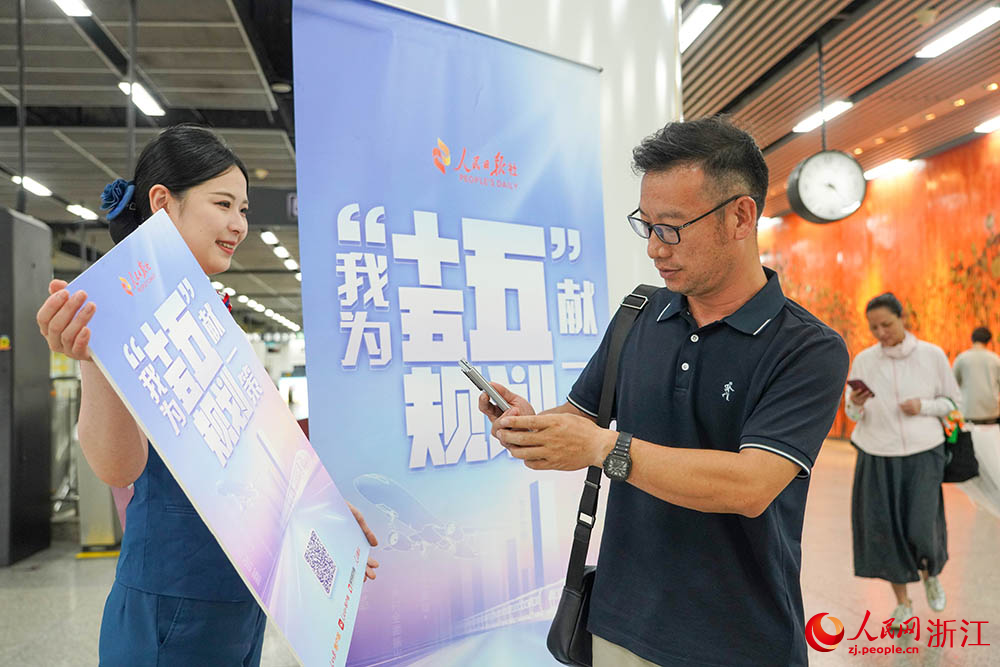 6月11日，在杭州地鐵1號線，杭港地鐵“五心服務隊”隊員引導乘客參與“我為‘十五五’規劃獻一策”活動。人民網 章勇濤攝
