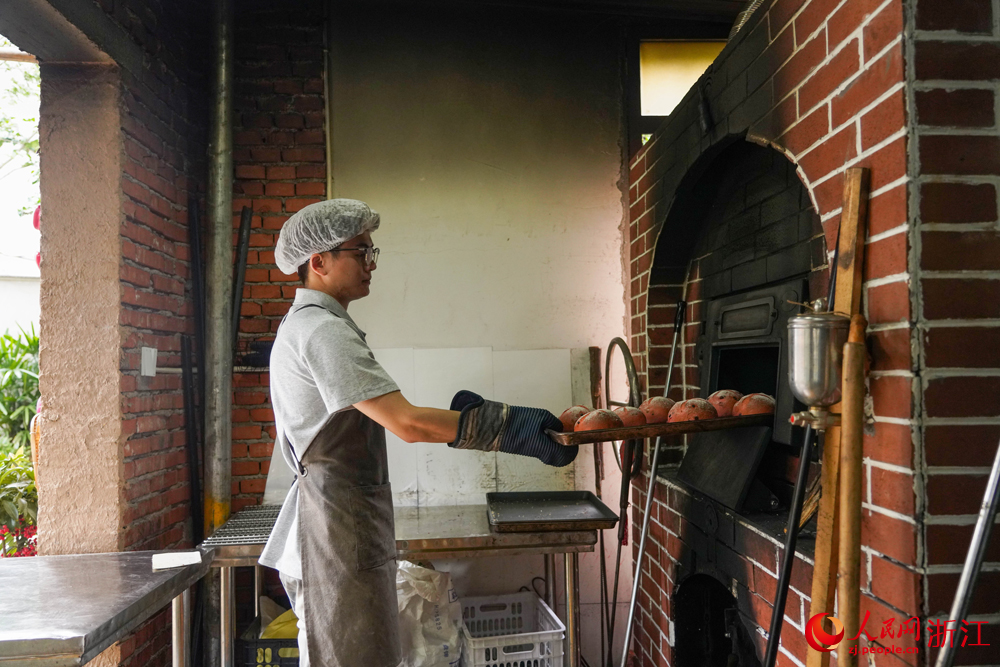 6月25日，寧波市寧?？h躍龍街道溪南劉村，工作人員正在取出烤好的面包。該村一處由自家老房子改建而成的庭院式面包房，已成為當地典型的小院經濟代表。人民網 章勇濤攝