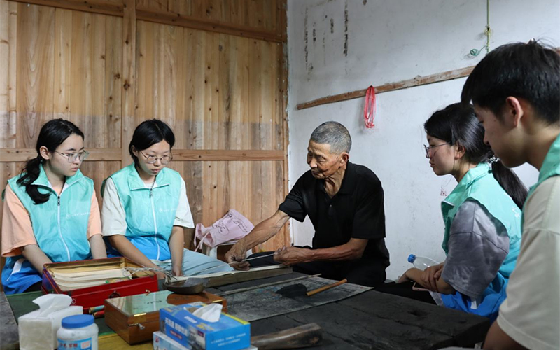 國家級非遺代表性項目傳承人為實踐團隊演示藥發木偶搓引線步驟。王蕊攝