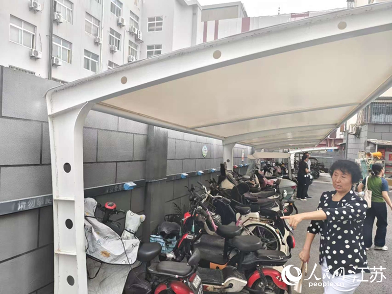 王立華為記者展示小區內新增的車棚和充電樁。